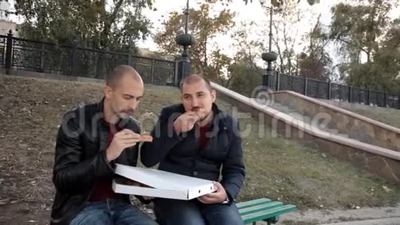 两个人坐在公园里吃披萨和鸡肉聊天视频的预览图