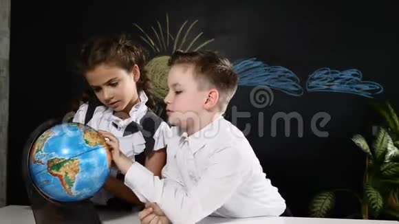 学校观念小学生们坐在桌子上桌子上放着一个地球仪孩子们选择度假旅游的地方视频的预览图