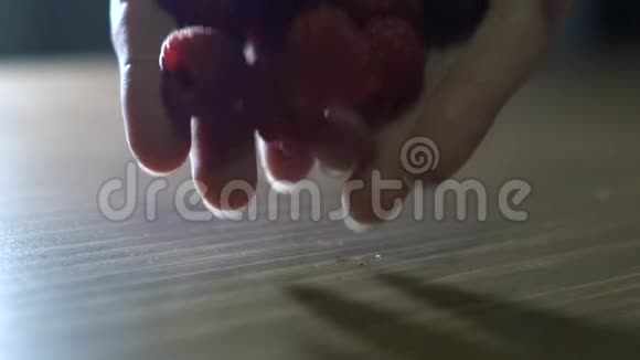女孩倒出木桌上的覆盆子浆果视频的预览图