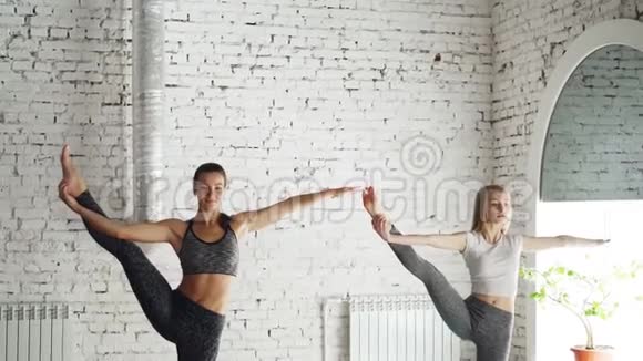 迷人的年轻女孩与专业教练进行单独的瑜伽练习并进行站立平衡视频的预览图