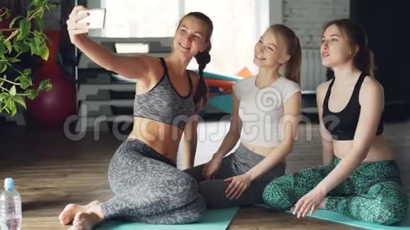 有魅力的年轻女性在健康中心的轻型现代健身房瑜伽课后自拍女人穿着视频的预览图