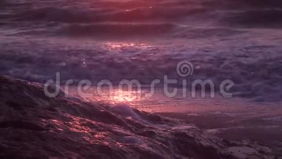海浪泡沫海浪在潮湿的沙滩上黑暗的大海在橙色日落的背景下视频的预览图