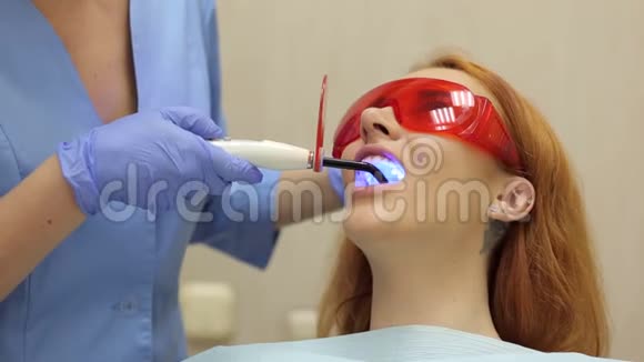牙医的女孩牙医医生用紫外线灯照在她的牙齿上视频的预览图