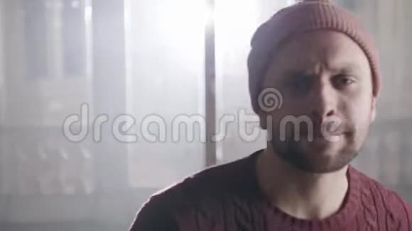 动态相机显示年轻的棕色眼睛男子在套头衫在空房间里饶舌视频的预览图