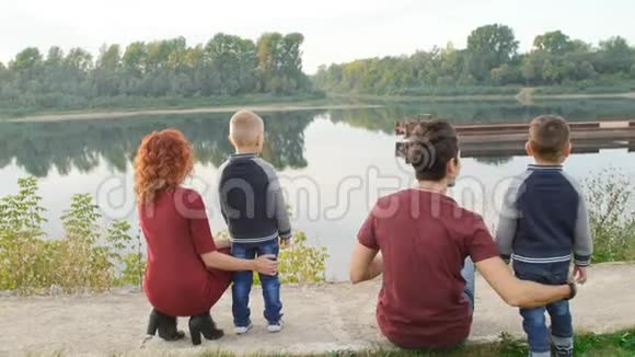 幸福的年轻家庭有两个儿子在河边的公园散步和休息家庭和关系概念视频的预览图