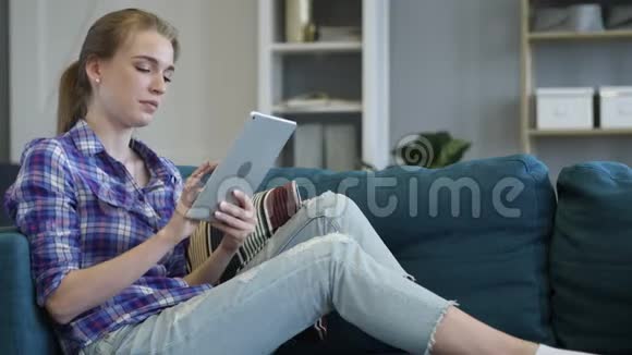 头痛的女人坐在沙发上用平板电脑视频的预览图