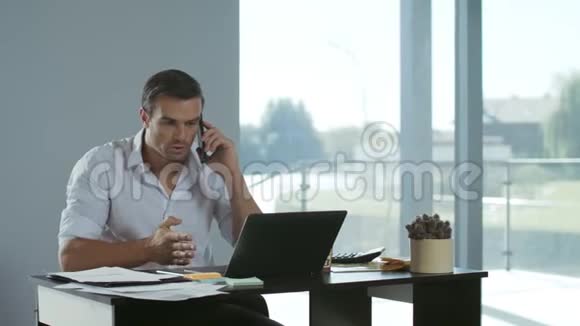 在笔记本电脑工作的商人专心致志的男人在说手机视频的预览图