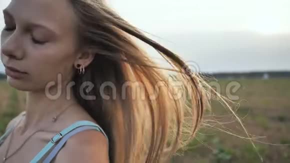 棕色头发的年轻女孩的长发在傍晚的阳光下随风飘散视频的预览图