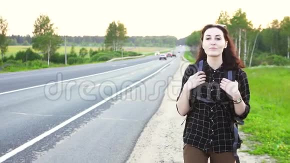 Hitchhiker女孩带着旅游背包在路上行走视频的预览图