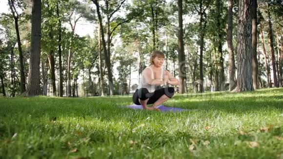 四K镜头40岁的女人在当地公园的垫子上做健身运动照顾他们的精神和视频的预览图