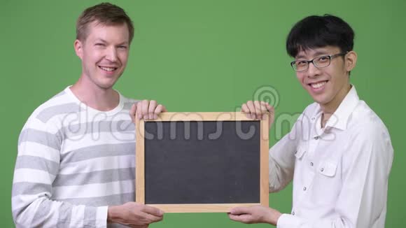 两个快乐的年轻多民族商人一起拿着黑板视频的预览图