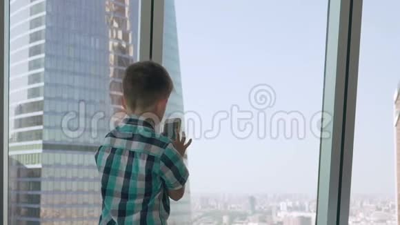 孩子们用他的智能手机在摩天大楼的背景下拍照大都市的现代儿童使用视频的预览图
