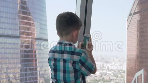 孩子们用他的智能手机在摩天大楼的背景下拍照大都市的现代儿童使用视频的预览图