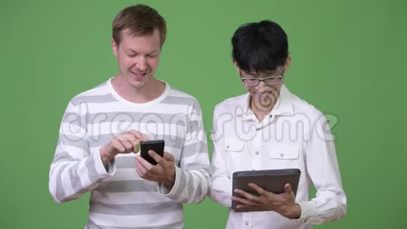 两个快乐的年轻多民族商人使用电话和数字平板电脑来社交媒体的概念视频的预览图