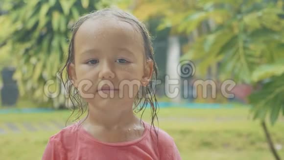 一幅5岁的女孩在热带雨中看镜头的肖像视频的预览图