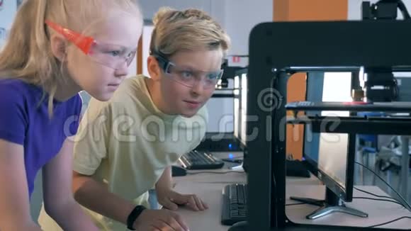 孩子们用3D打印机工作男孩和女孩在一个有3D打印设备的科学实验室工作视频的预览图