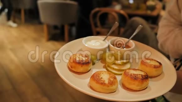 准备好的奶酪薄煎饼放在盘子里上面有梨子片和葡萄片里面有酸奶油和蜂蜜服务员留着视频的预览图