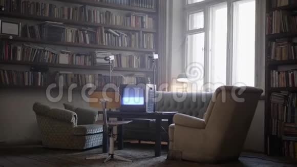 成熟的男人在配备有旧沙发扶手桌子书架的房间里散步视频的预览图