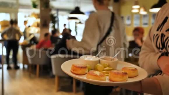一个服务员正拿着一个盘子里面有奶酪薄饼和果酱和酸奶油照相机在盘子里飞来飞去视频的预览图
