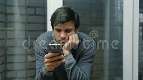 坐在窗台上的人正在用手机读东西视频的预览图