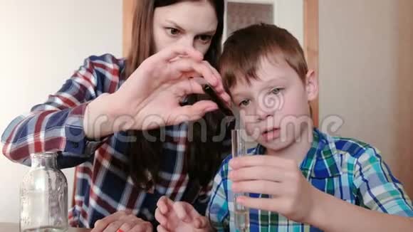 在家做化学实验女人把红色的油漆放在试管里男孩手里拿着水视频的预览图