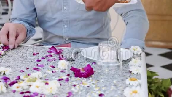 侍者给坐在桌旁的一对夫妇端来早餐桌上摆满了鲜花视频的预览图