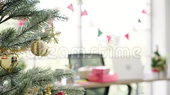 快乐的亚洲女人拿着圣诞装饰品在她的办公室装饰圣诞树视频的预览图