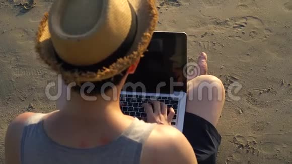 匿名的自由职业者在海边使用笔记本电脑视频的预览图