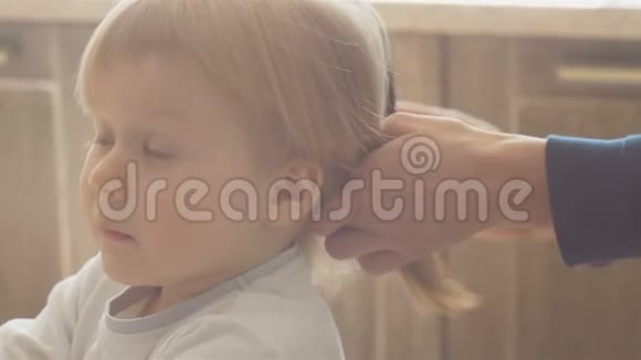 妈妈把小女儿的尾巴头发给一个三岁的小女孩梳头一个金发女孩视频的预览图