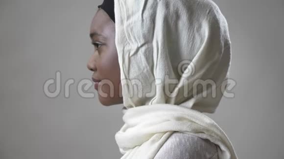 戴头巾的年轻非洲穆斯林女孩转过头在镜头前观看宗教概念灰色背景视频的预览图