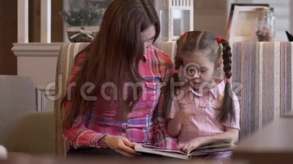 可爱的年轻母亲和美丽的女儿在菜单上翻来覆去视频的预览图