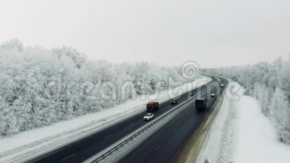 在冬天的暴风雪中汽车在雪覆盖的道路上行驶视频的预览图