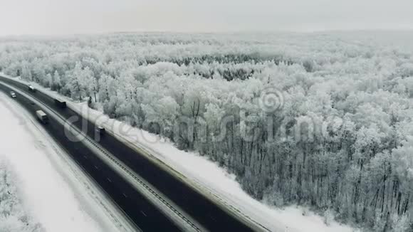在冬天的暴风雪中汽车在雪覆盖的道路上行驶视频的预览图