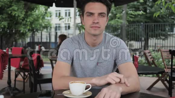 一个男人坐在咖啡厅露台的窗户上视频的预览图