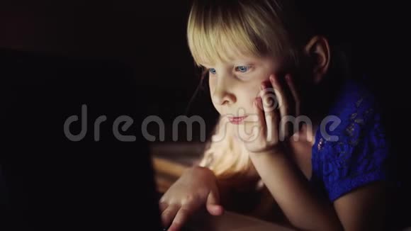 小女孩在笔记本电脑上看起来很卡通发光的笔记本电脑屏幕照亮孩子脸视频的预览图
