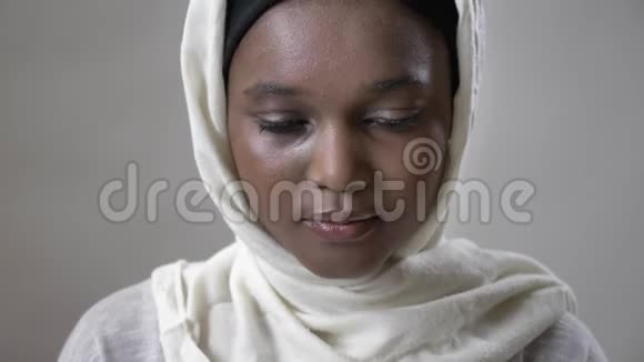 戴头巾的年轻悲伤的非洲穆斯林女孩抬头看着镜头宗教概念灰色背景视频的预览图