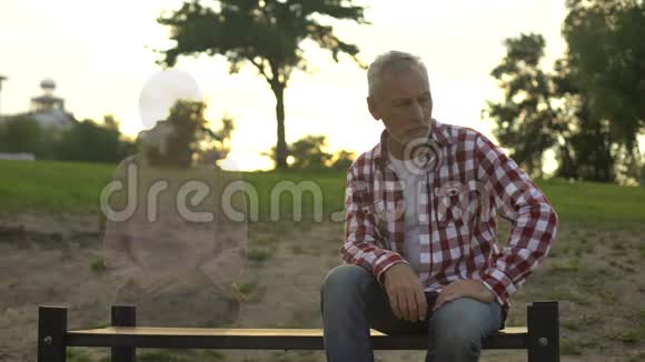 沮丧的老人坐在长凳上妻子出现在旁边失去悲伤回忆视频的预览图
