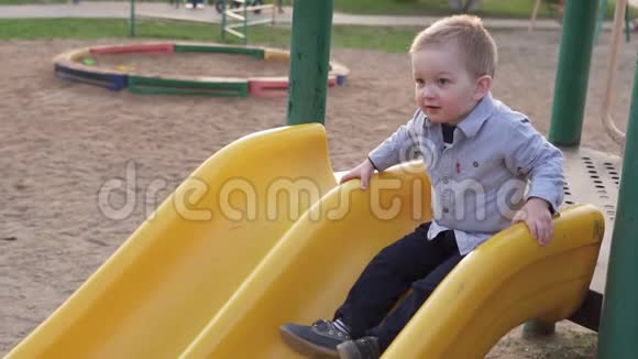 可爱的小男孩从孩子们的滑梯上下来公园里视频的预览图