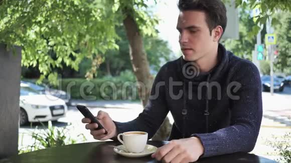 年轻人坐在咖啡厅露台上打电话自拍视频的预览图