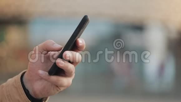 年轻人的手在购物中心附近的街道上使用智能手机交流网上购物聊天社交视频的预览图