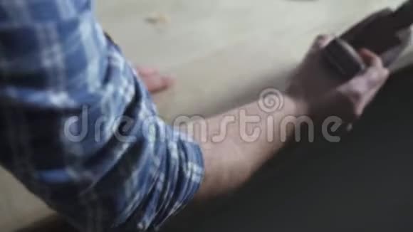 一个穿衬衫的木匠手拿着一架飞机把刨花紧紧地放在车间里视频的预览图