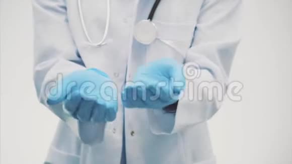一位美丽的年轻医生穿着白色长袍和蓝色手套在这段时间里它是在灰色背景上视频的预览图