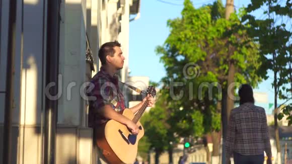 男子街头音乐家穿着衬衫在日落时分弹吉他视频的预览图