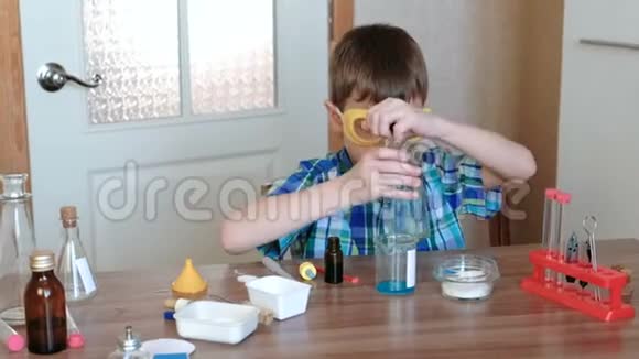 家庭化学实验男孩用另一种蓝色物质把水倒进烧杯里视频的预览图