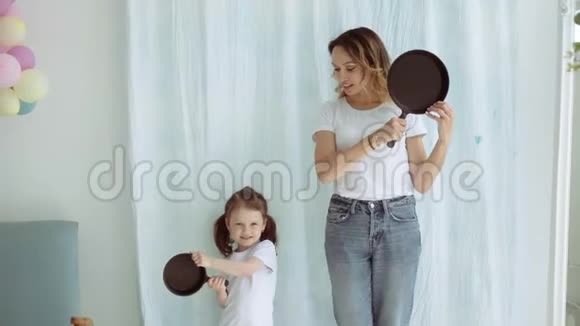 一个手里拿着煎锅的小女儿的女人站在墙边一个漂亮的小女孩视频的预览图