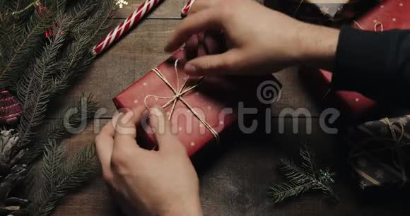 男子手把礼品盒用装饰线绑好后用红纸包在木桌上准备视频的预览图