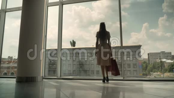 年轻漂亮女孩的剪影去商场橱窗拿着包购物理念时尚理念视频的预览图