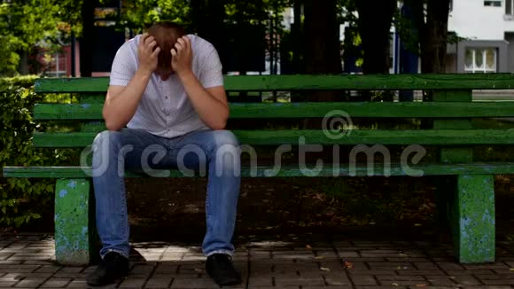 一个年轻人坐在长凳上低着头抱着头有问题视频的预览图