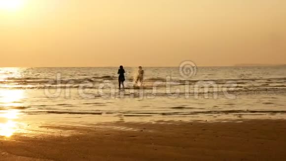 4K日落时姐姐和哥哥在海滩上奔跑和玩耍的剪影美丽快乐的青少年朋友视频的预览图
