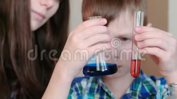 在家做化学实验男孩在试管和烧瓶中检查两种不同颜色的液体视频的预览图